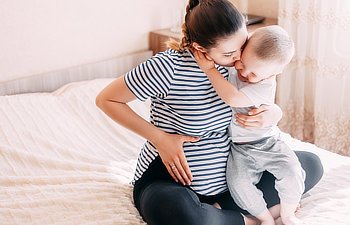 pregnant woman playing and hugging with her second baby